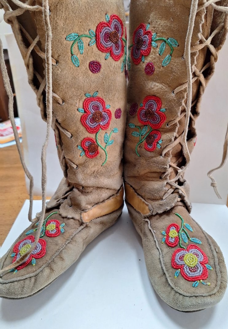 Antique Native American Beaded Moccasin Boots: An antique pair of Native American Eastern Woodlands beaded moccasin boots, attributed to the Iroquois (Haudenosaunee) tradition. Constructed from soft hide in a tall boot form, the moccasins are deco