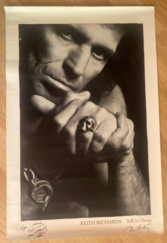 Keith Ricahards & Annie Lebovitz Signed Poster: This lot features a black-and-white poster depicting Keith Richards, associated with his 1988 solo album Talk Is Cheap, with the printed text visible along the margin. The poster is signed by both Ann