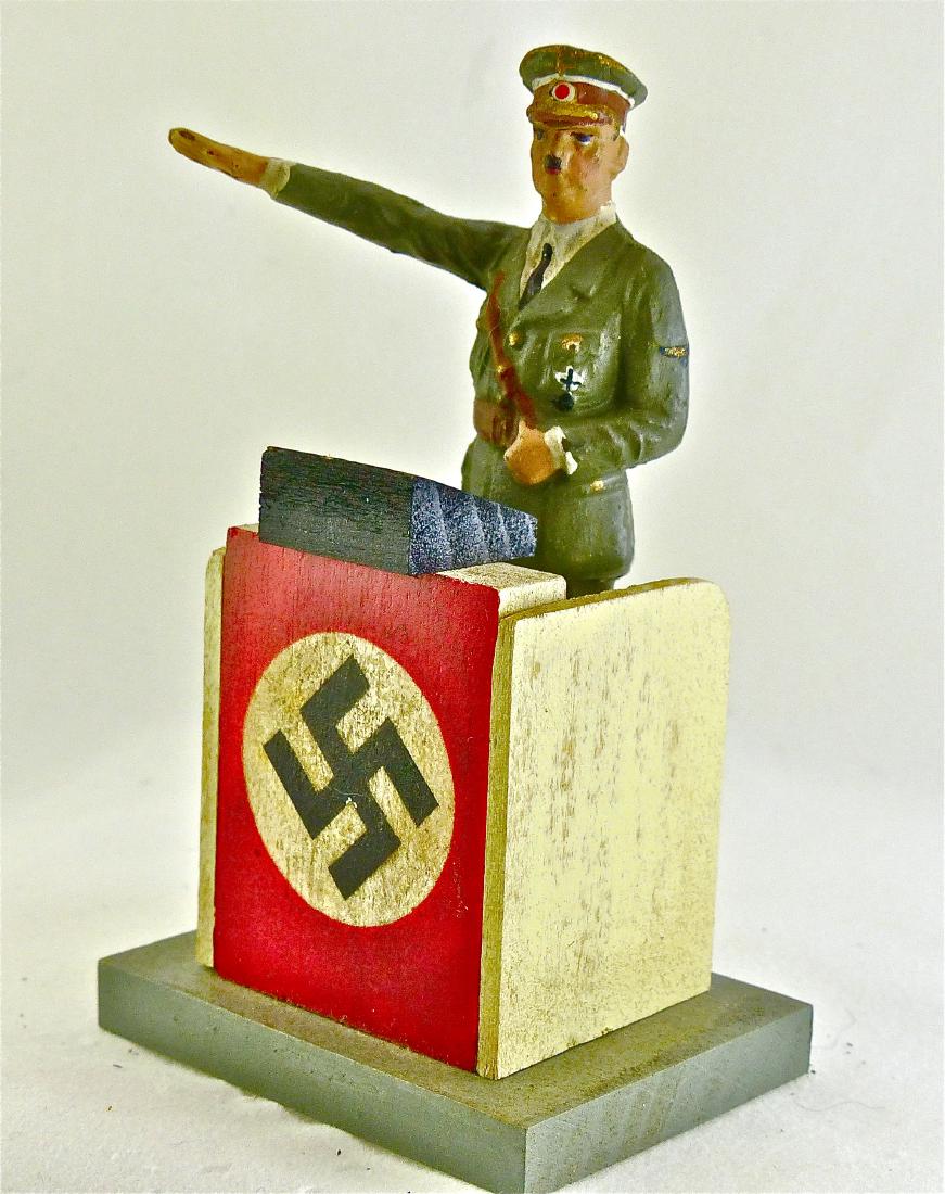 Lineol Hitler in Army Uniform Heiling at Podium: Fine example of Hitler figure. No cracks and hardly any wear. Excellent face and paint quality. Podium is an exact postwar copy of a Lineol podium. 2 Pieces. 7.5 cm. Figure made Only 1938-40. Excellen