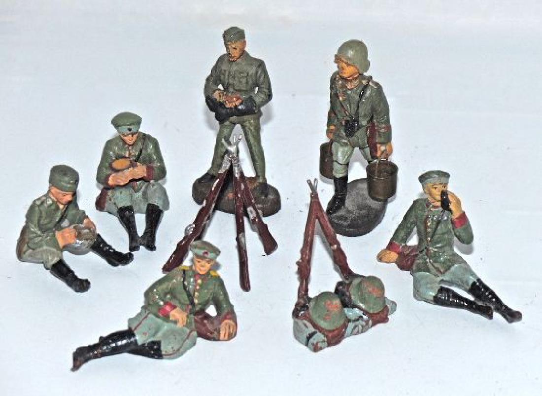 6 Elastolin Camp Figures 2 Rifle Stacks: Figure polishing boots shows some touch-up. Other figures with few minor cracks and excellent paint. 2 Rifle stacks with very little wear. 8 Pieces. 7 cm. Reichwehr figures with red cuffs date to 1933