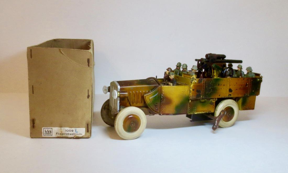 Lineol Fliegerabwehrauto with AA Gun: #1009. 9 pieces. 65 mm scale. Very good condition. Windup in good working condition. Soldiers have some paint wear and cracks. Comes with original box (bottom only).