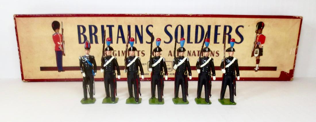 Britains #1437 Italian Army Carabinieri: Carabinieri marching with rifles at the slope, dressed in traditional uniforms with colorful plumes. Post war with ROAN box. 7 pieces. Excellent condition. Box very good (one corner split).