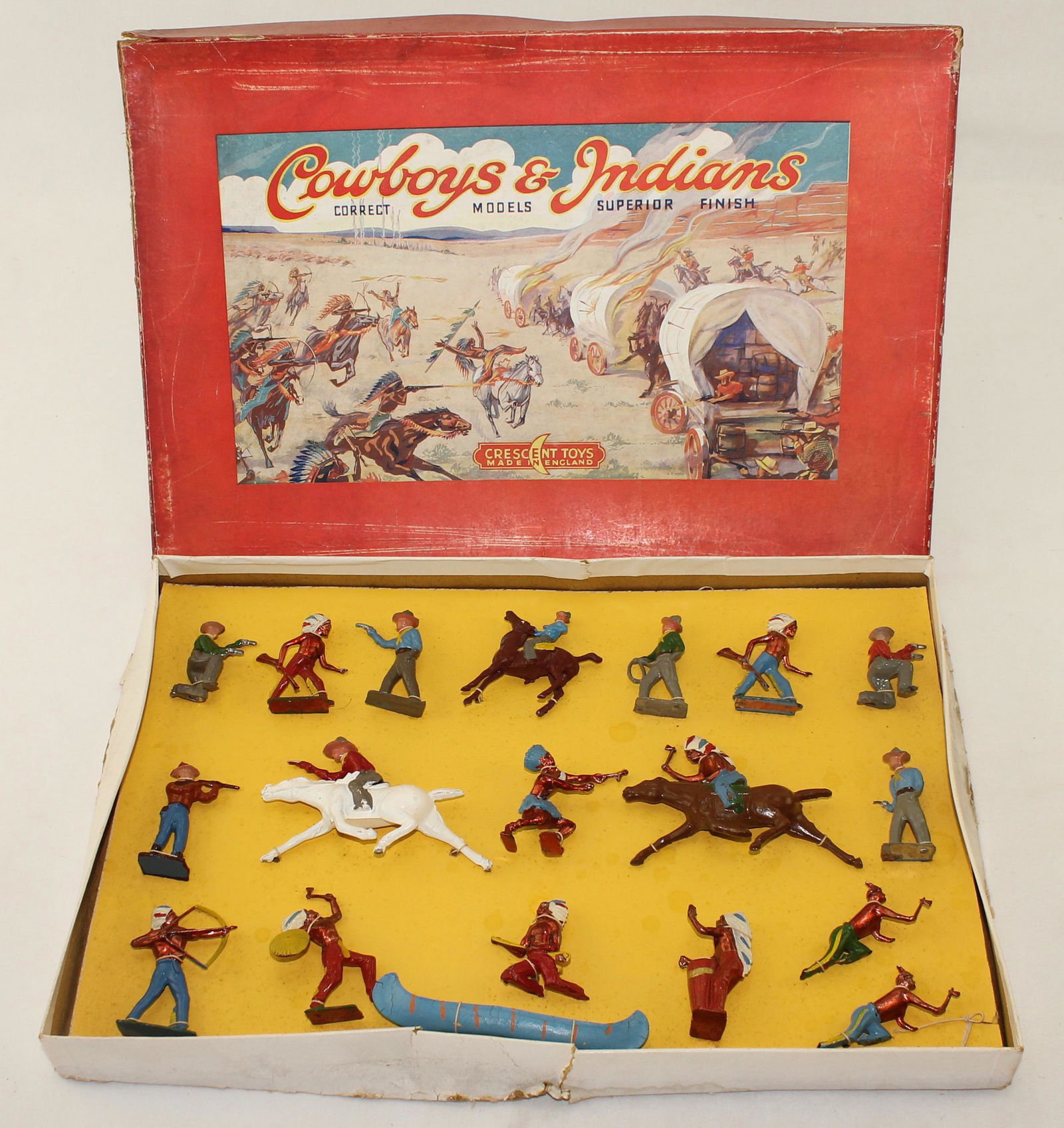 Crescent Cowboys and Indians Display: Cowboy and Indian Display. 19 Pieces. Tied in Box. Condition Good. Paint Flaking on Canoe. Box Fair with Edge Damage and Warped Lid.