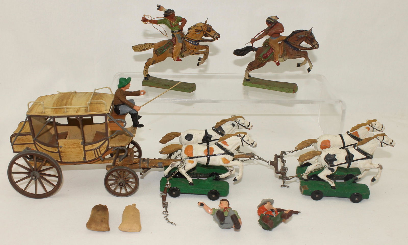 Elastolin Lot Stagecoach with Horse Team: 7 cm Western Stage Coach with 4 Horse Team, Riders and 2 Mounted Indians. 10 Pieces. Condition Fair to Good. Coach Luggage Railing Damaged, Horse's Paint Cracked and Traces Incomplete or Damaged. Seat