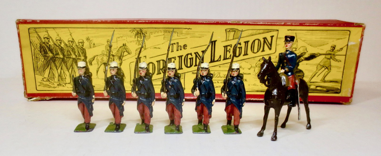 Britains #1711 French Foreign Legion: Foreign Legionnaires, marching at the slope with Mounted Officer. Post war, with illustrated box. 7 pieces. Excellent to good condition (one broken rifle). Box good (one top corner tear).