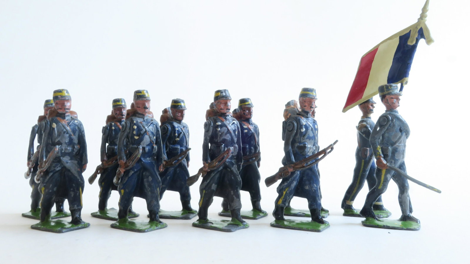 Britain's Paris Office Chasseurs a Pieds: at the trail with flag bearer 1916 square base; dark blue greatcoats; only offered by the Paris Office Fair-good; 4 rifle tips gone, some chips; flag bearer fair, flag retouched; other officer poor-fa