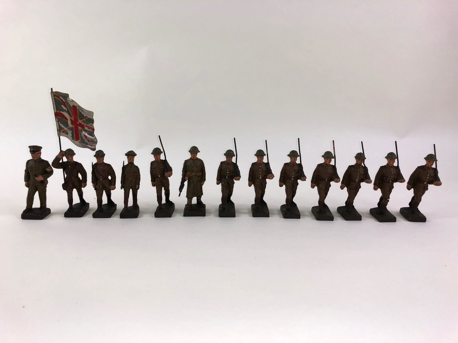 Lineol British Army Composition at the March: 13 pieces in fair to good condition. This group is about 2-1/2 inches tall. Many typical stress crack and paint issues. Nothing broken. Bare metal gun barrels. A worn but nice metal Union Jack.