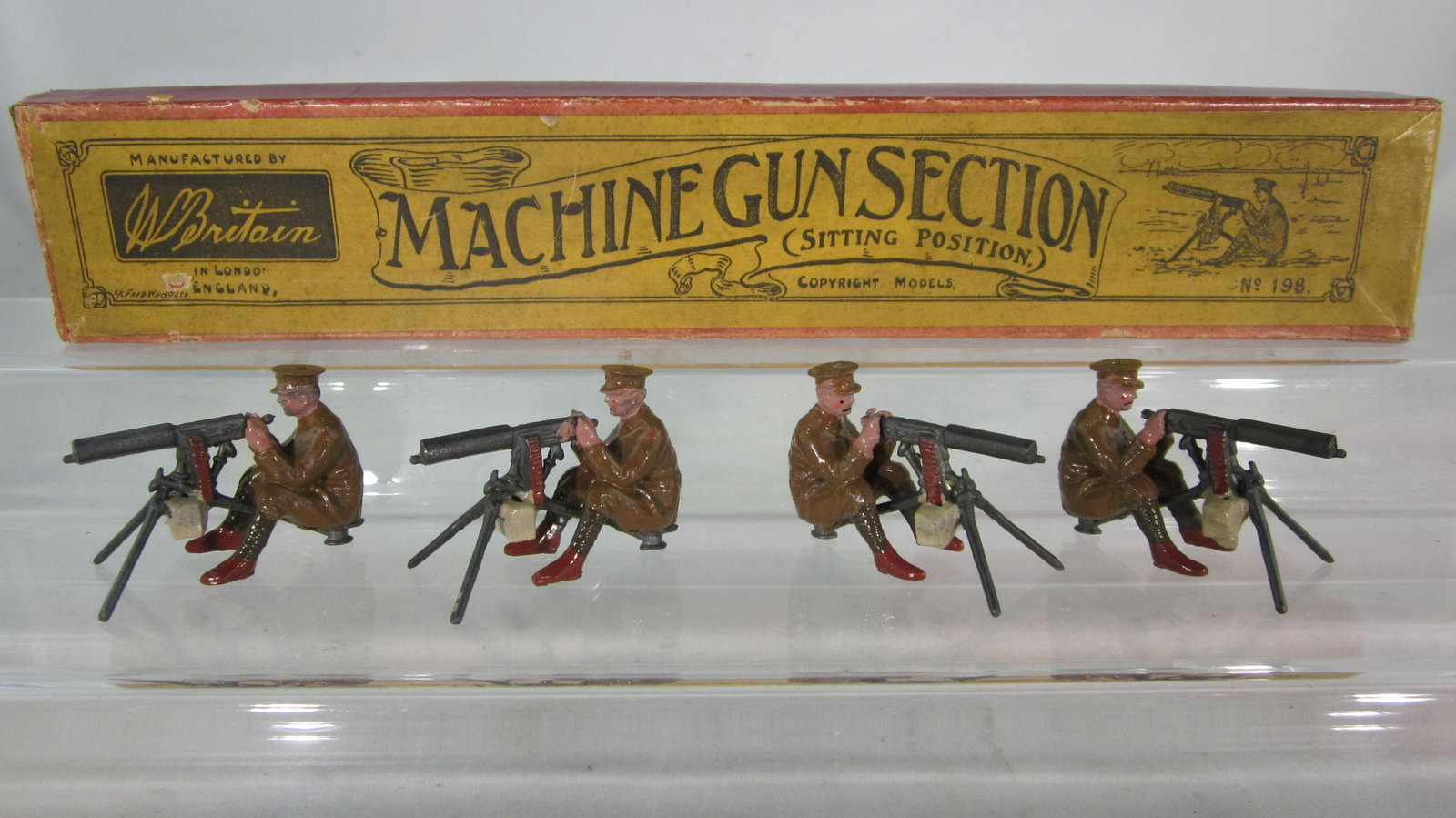 Britains Set #198 Machine Gun Section Sitting.: Boxed seated Machine Gunners. Early issue Gunners in brown boots with 1st version Maxim guns. 4 pieces circa 1920. Condition Mint in unusual long skinny box with Whisstock label. Very nice example.