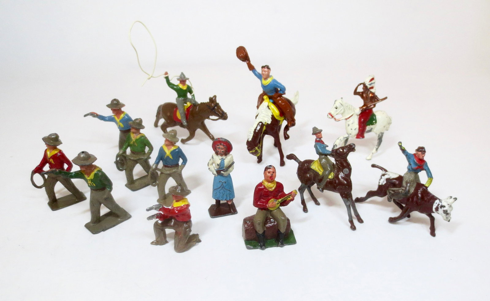 Crescent Wild West Figure Assortment: Rodeo Cowboys, Cowboy Playing Banjo, Cowboys Firing Pistol, Indian Chief on Mounted Horse, and Annie Oakley. 13 pieces. Excellent to very good condition (Annie Oakley's rifle butt broken). Unboxed.