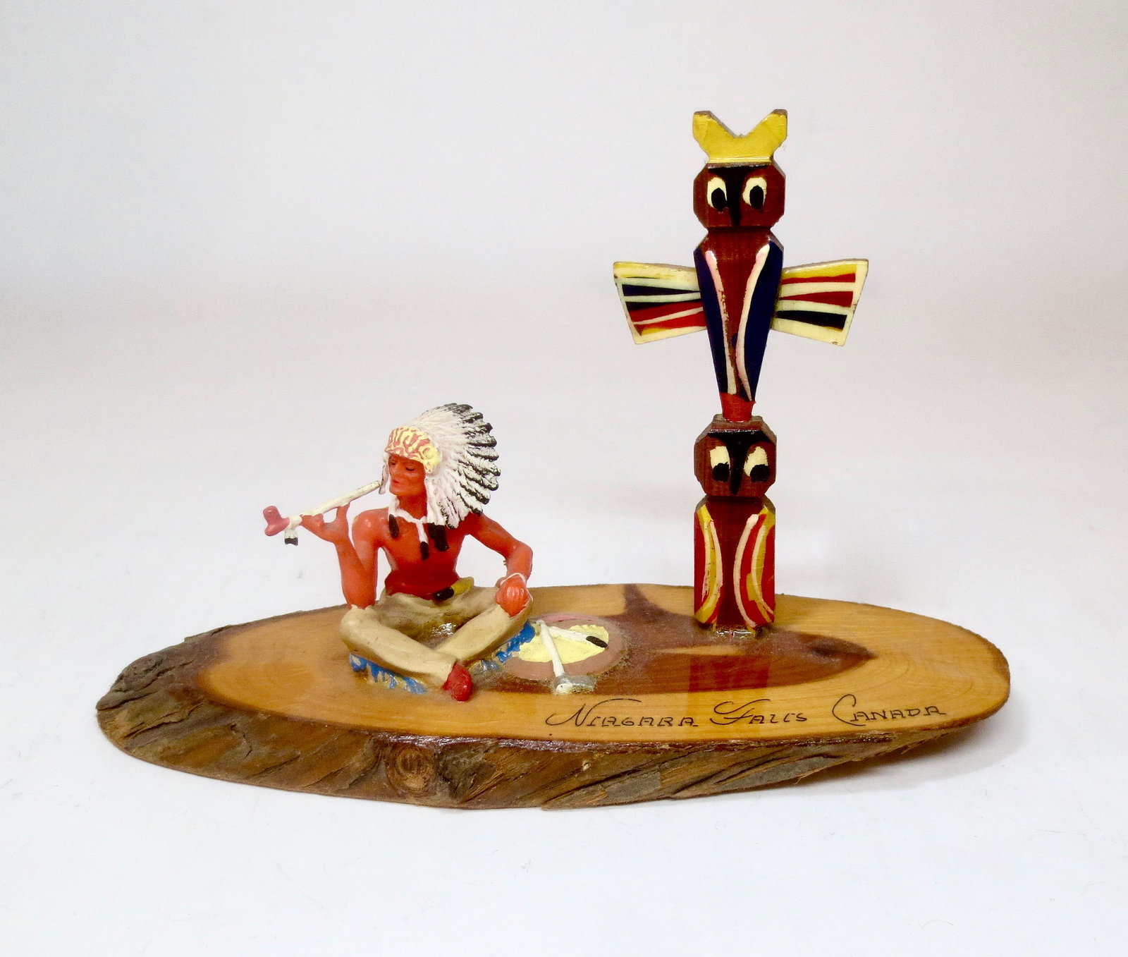 Vintage American Indian Souvenir Figure: Wonderful Indian Chief smoking peace pipe under the totem pole. Wooden base marked Niagara Falls Canada. 4" tall. Near mint condition. Unboxed.