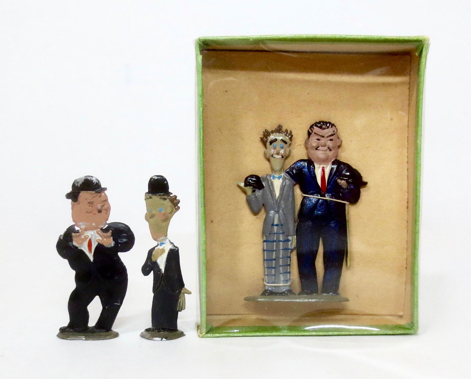 Mignot "Laurel and Hardy" Figures: Circa 1935. Wonderful depictions of the well loved comedic duo. 3 pieces. Two sets, one still mint in box, the other excellent, with some paint loss on Ollie's derby.