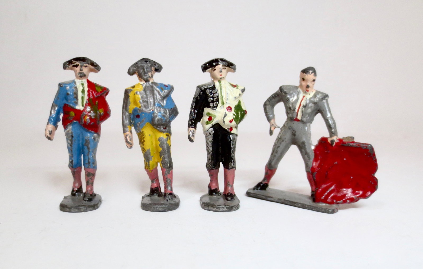 Unusual Matador Figures: Three Matadors entering the ring, while another fights with his red cape. 4 pieces. 50mm. Good to fair condition, with paint loss.