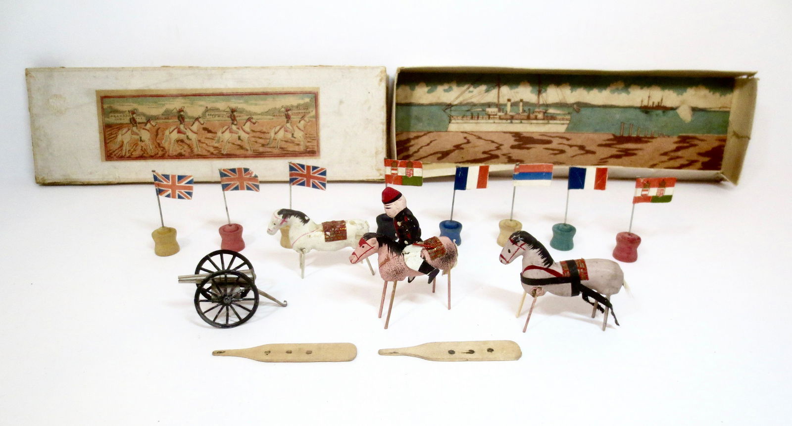 Vintage Wooden Cavalry Set: Mounted Wooden Soldier with wooden horses, flags from various nations, and metal cannon. Japanese maker. Mounted soldier measures 3-1/4" tall. 14 pieces. Very good condition. Box fair (surface wear th
