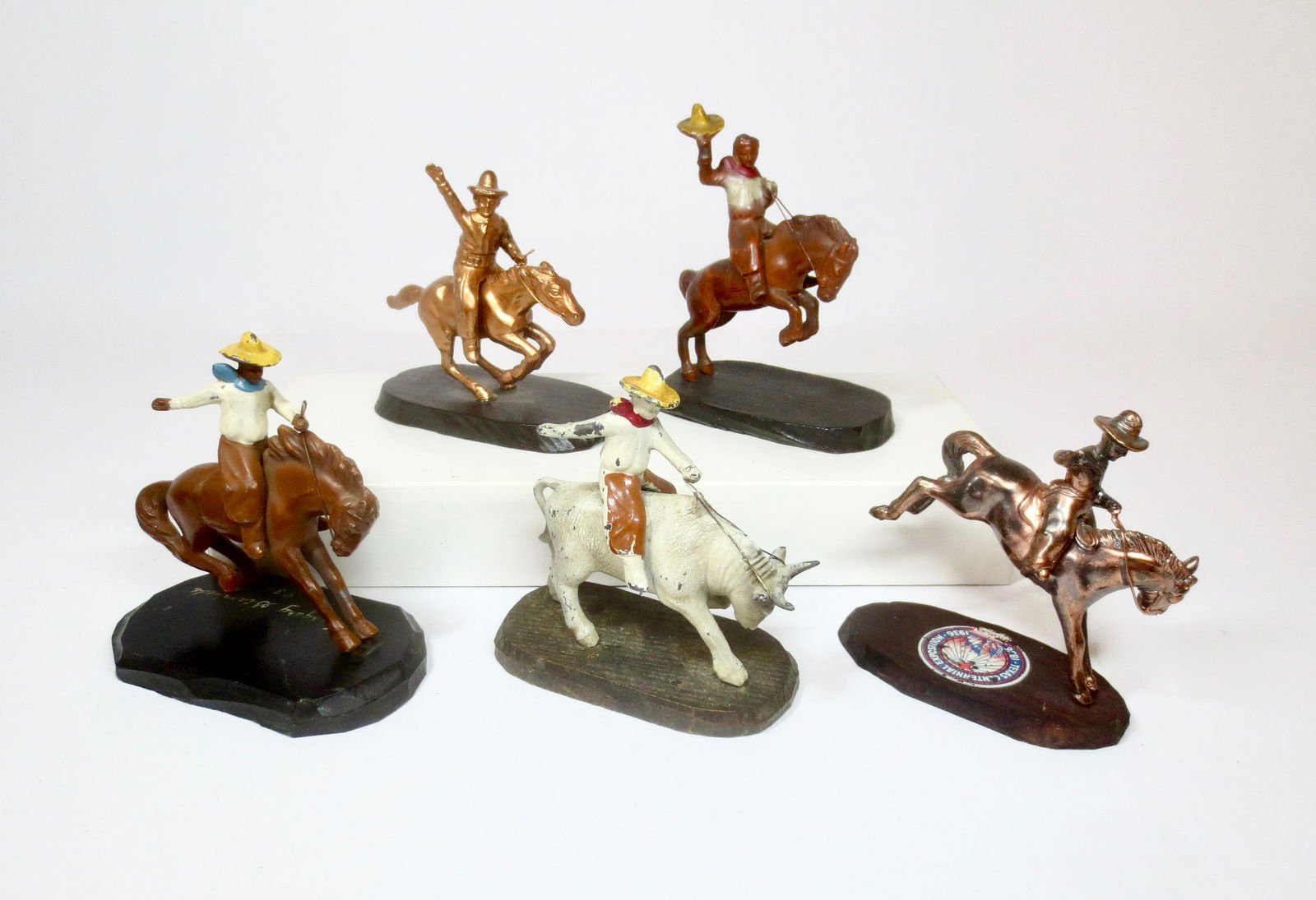 Vintage Rodeo Souvenirs: Cowboys on Bucking Broncos and Bull. 5 pieces. From the Cavalry Stampede of 1931, The Texas Exposition Centennial of 1936, and Montreal Canada. Two pieces unmarked. Measure 3-1/2" to 4" tall. 5 total