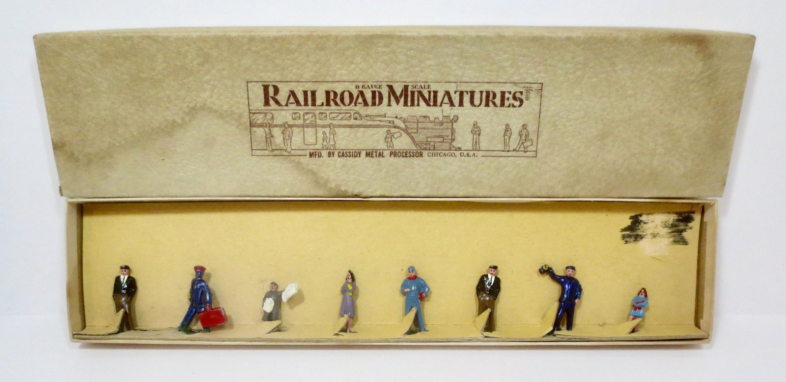 Jones Cassidy "Railroad Miniatures" Set: Station crew, Newsboy, and Passengers. 8 pieces. Mint condition. Box good (some stains on the top).