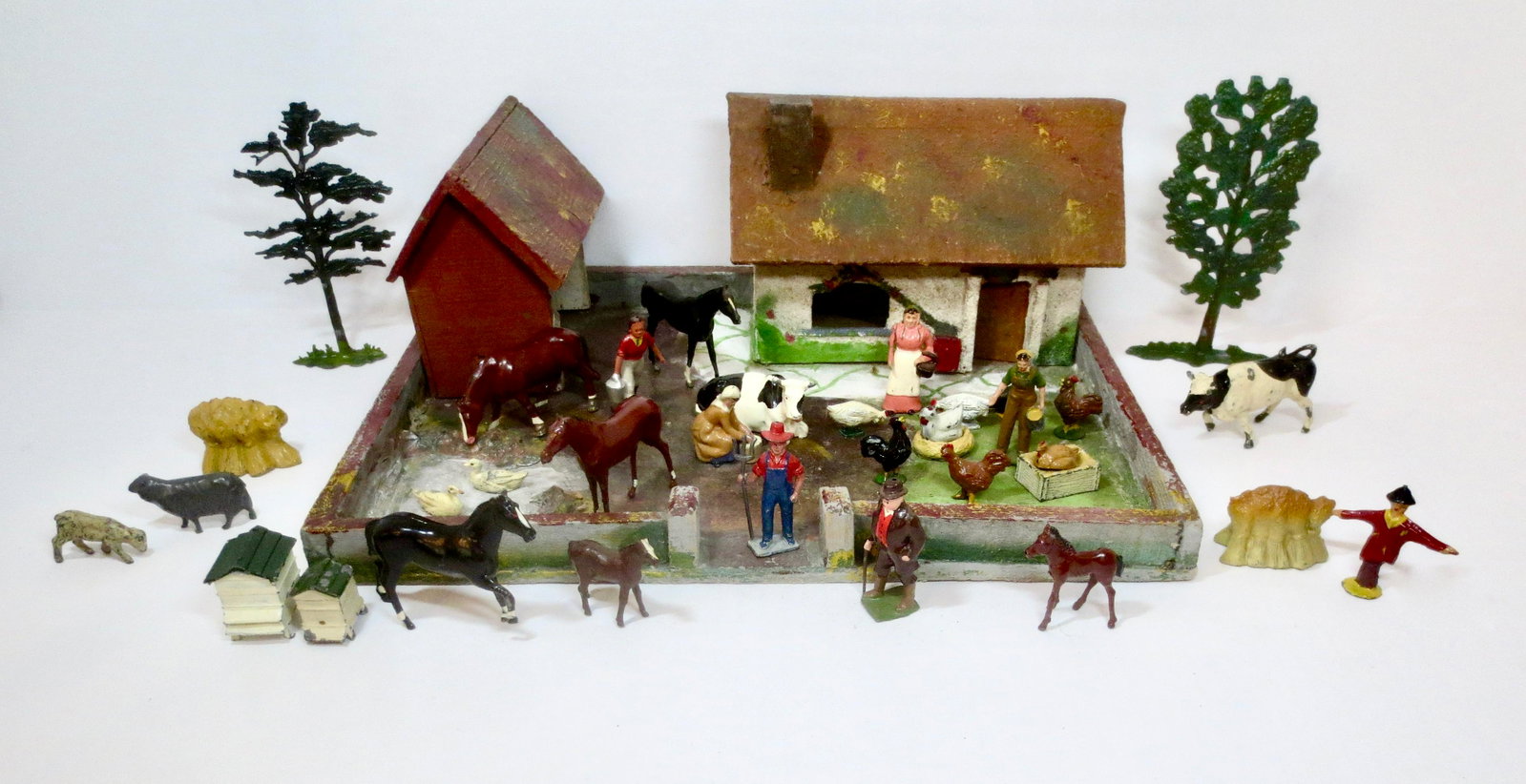 British Hollowcast Farm Figures with Wooden Farm: Assorted Farmers, Wives, Land Girl, Cows, Roosters, Chickens, Chicks Pigs, and Horses. Made by Britains, Johillco, Crescent and more. Comes with a wooden farm that measures 11"x14". 38 total pieces. A