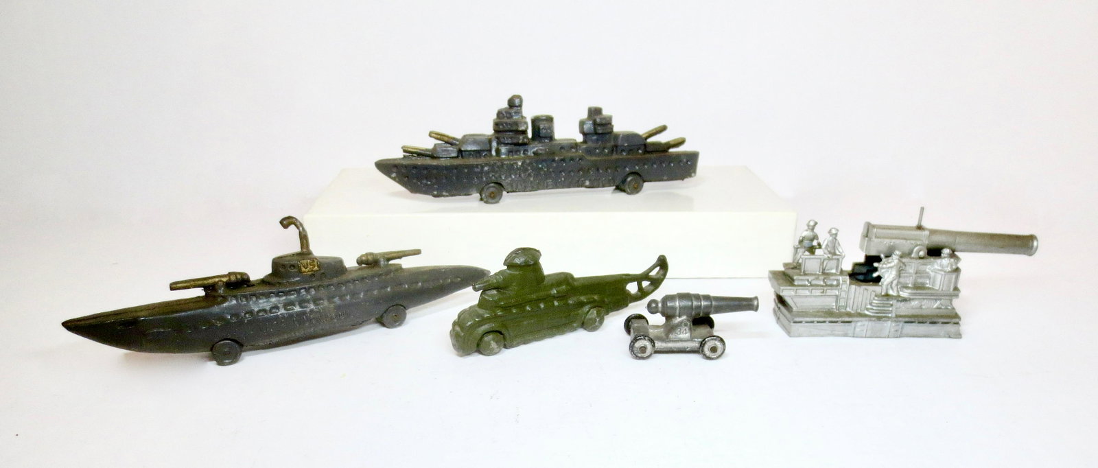 American Dimestore Military Toys: Includes two slush mold Battle Ships (The U.S.S. New Mexico and The Narwhal), a Kansas Toy Cannon, and a Barclay spring load Howitzer and crew. Pieces measure 2" to 7" long. 5 pieces. Excellent to ver