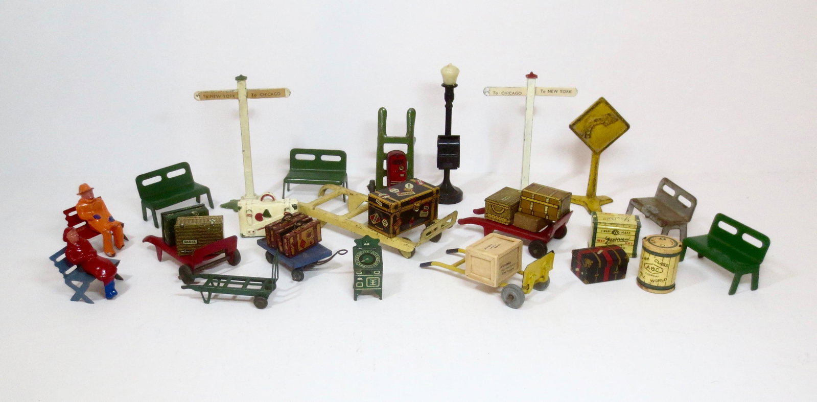 Assorted Tin & Lead Railway Accessories: Fine array of tin benches, dolly carts, baggage and lead figures & signs from an assortment of makers. 40mm to 150mm tall. 35 pieces. Excellent to very good condition. Unboxed.