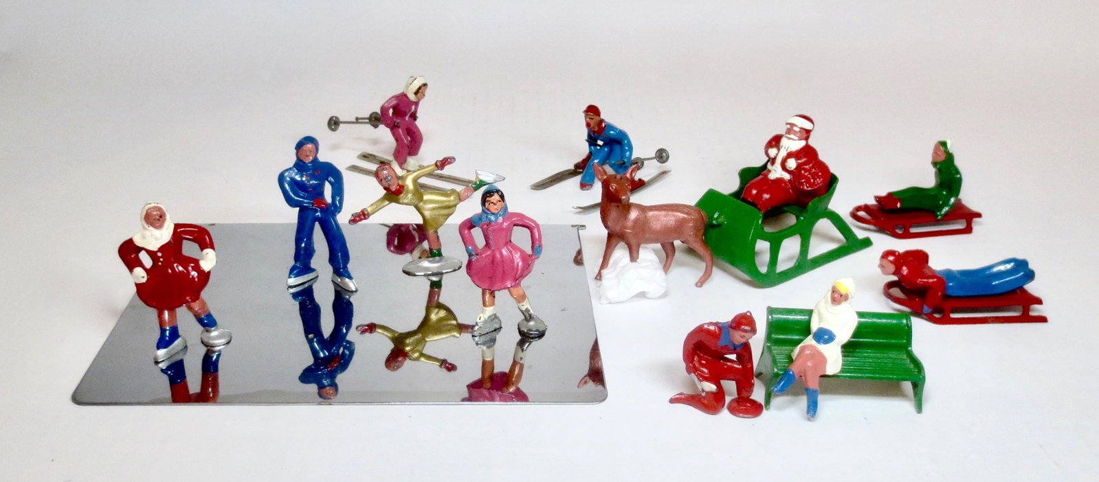 Barclay Dimestore Winter Figures Set: Skaters with frozen pond, Skiers, Sledders, and Santa in a deer drawn sleigh. 16 pieces. Excellent to good condition (one skier leg and one deer leg broken off). Unboxed.