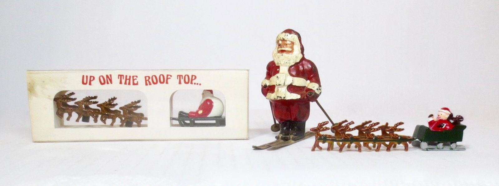 Dimestore Santa Figure Selection: Barclay Santa on Skis, with two miniature sleighs pulled by reindeer (one mint in box). 3 pieces. Excellent to mint in box condition.