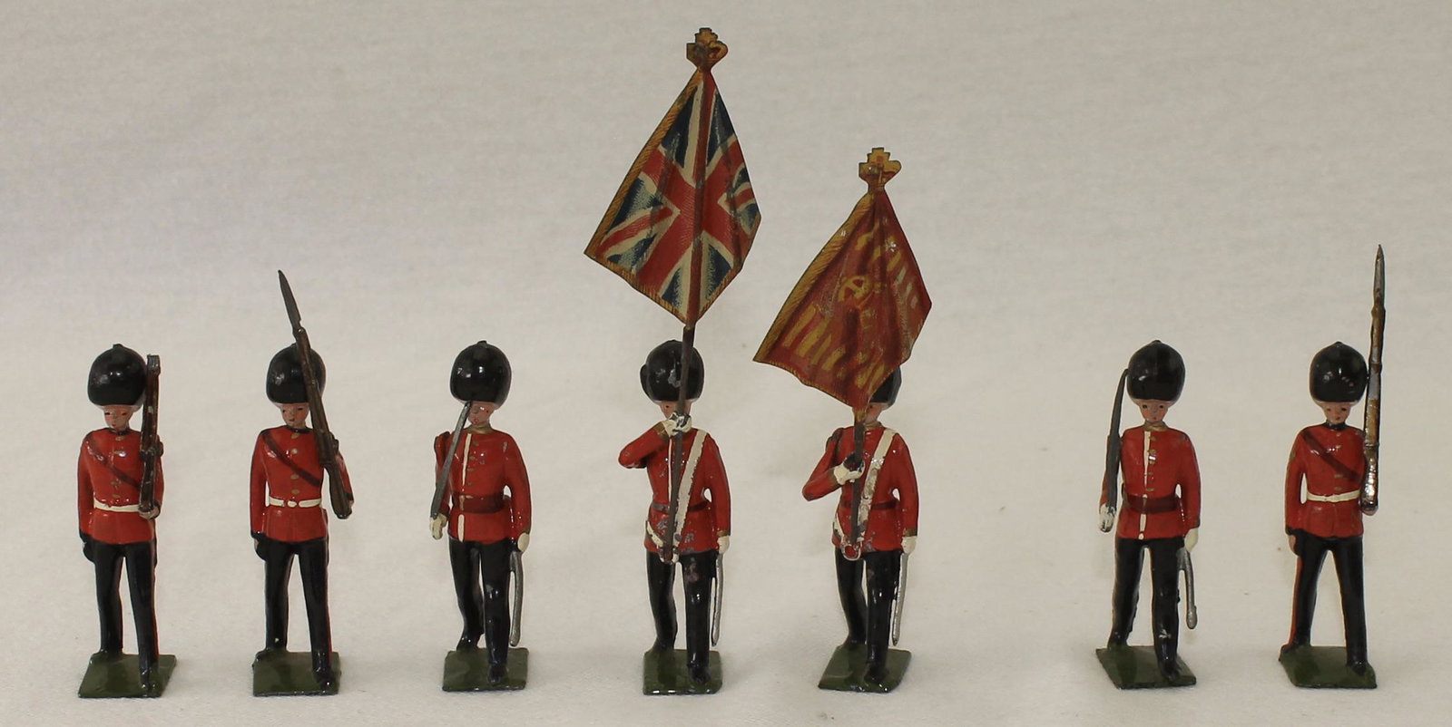Britains From #2084 Scots Guard Color Party: Includes 2 Foot Officers, 3 Troopers at the Slope, 2 Standard Bearers and Tin Flags. 9 Pieces. Condition Good to Very Good. One Rifle Barrel Broken. One Flag Bearer Head Glued. A Few Loose Arms. No Bo