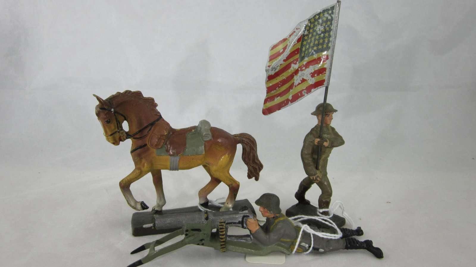 Lineol Horse, Flagman And Swiss Machine Gun.: UNBOXED 7cm Post War military horse, U.S. Infantry Flagbearer and Swiss lying machine gunner. 3 pieces. Condition of horse is excellent, small crack in left rear leg, paint is excellent. Flagman is ve
