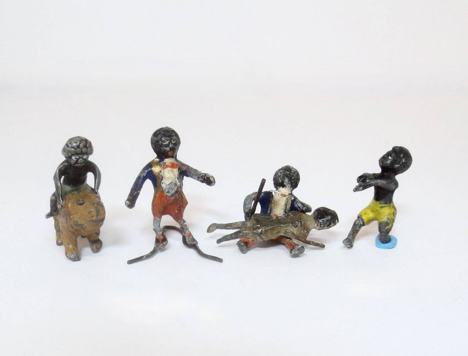 Heyde Golly Assortment: 4 pieces. 30mm. Golly riding a lion, Standing (crack in ankle), Spanking Peg Doll, and Running (missing foot). Fair to poor condition (missing foot).