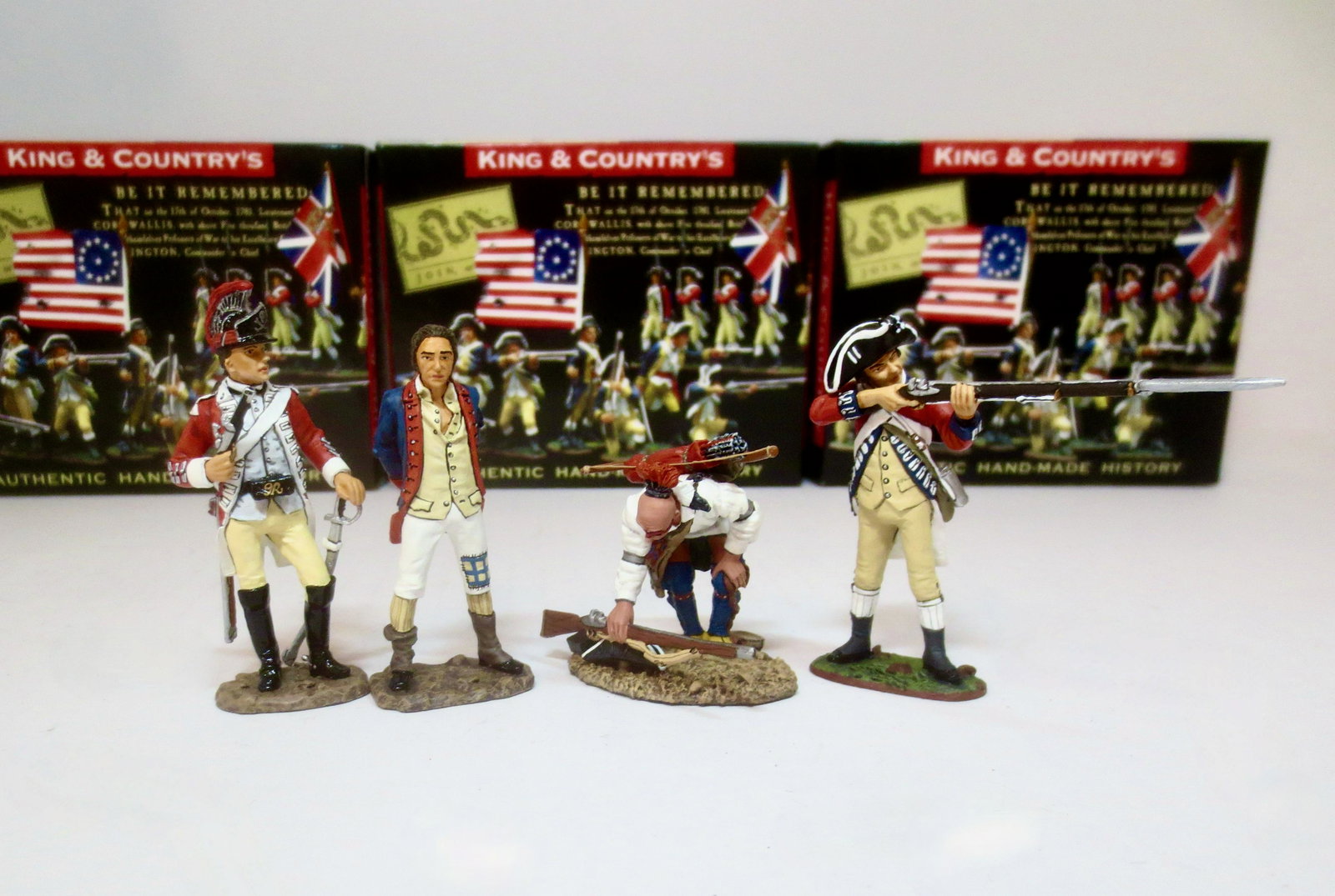 King & Country "American Revolution" Figures: Colonial Prisoner & Escort #BR059, "This Gun is Mine" Indian retrieving rifle #BR053, and British Infantry firing "Brown Bess" musket #BR048. All retired. 4 pieces. Mint condition. Boxes excellent.