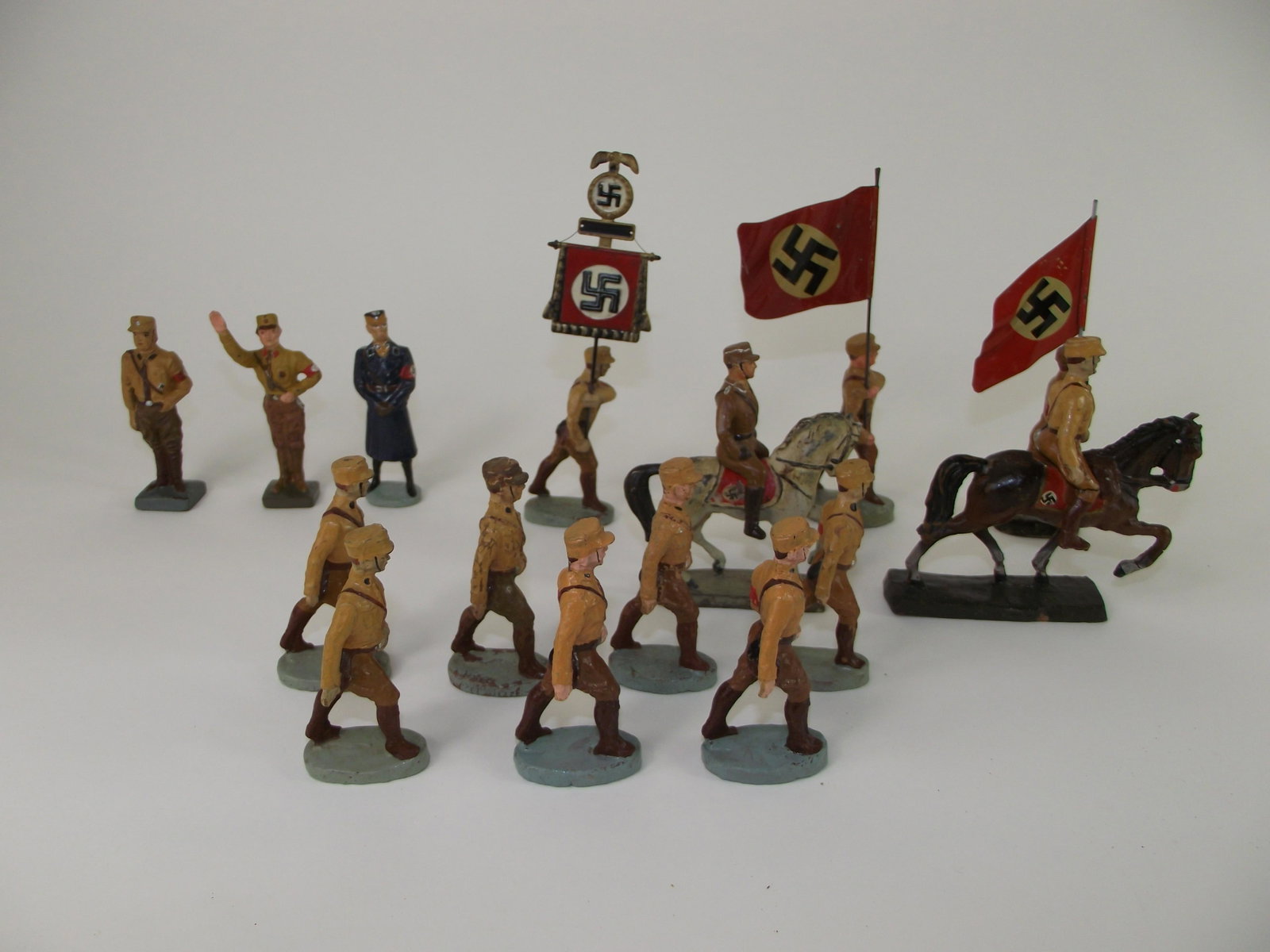 Lineol and Elastolin Nazi Brownshirts: 13 pieces in good overall condition. Tin flags, composition figures . A few pieces marked Elastolin. Others are marked Lineol and Gloria..