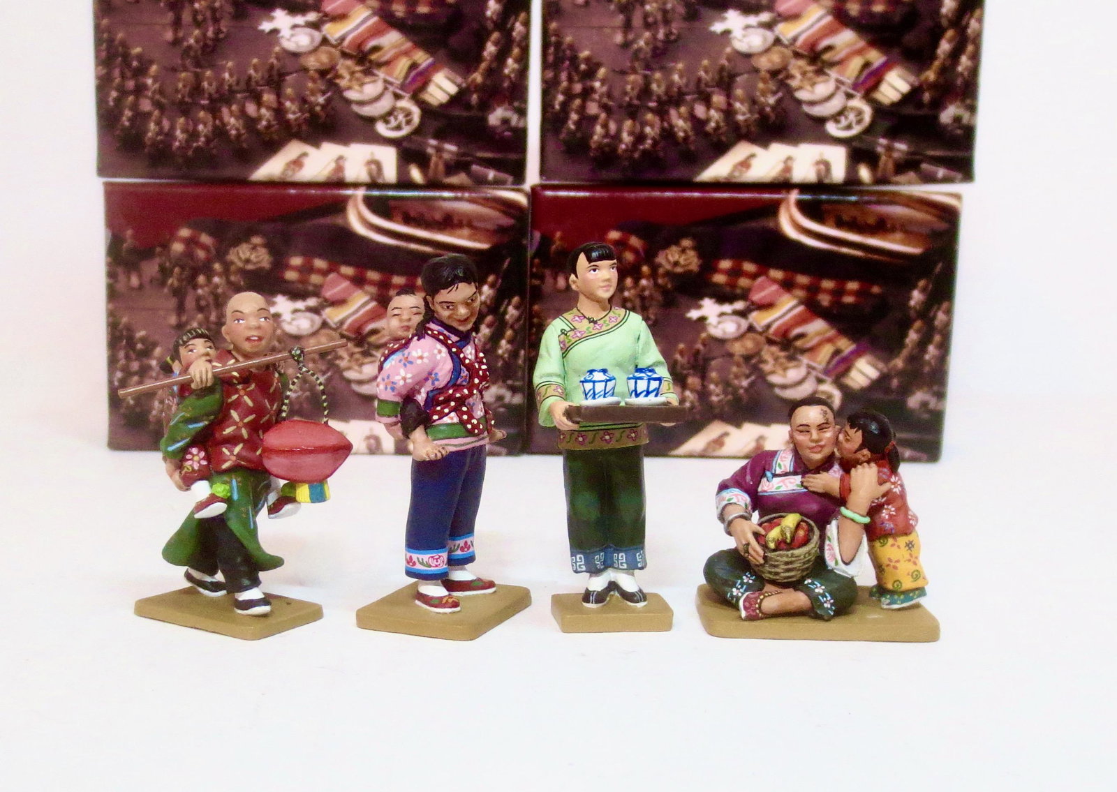 King & Country Streets of Old Hong Kong Figures: Mother & Child #HK216, The Tea Maid #HK211, Big Sister with Little Brother #HK207, and Happy Day #HK178. 4 pieces. Mint to near mint in boxes. Boxes excellent.