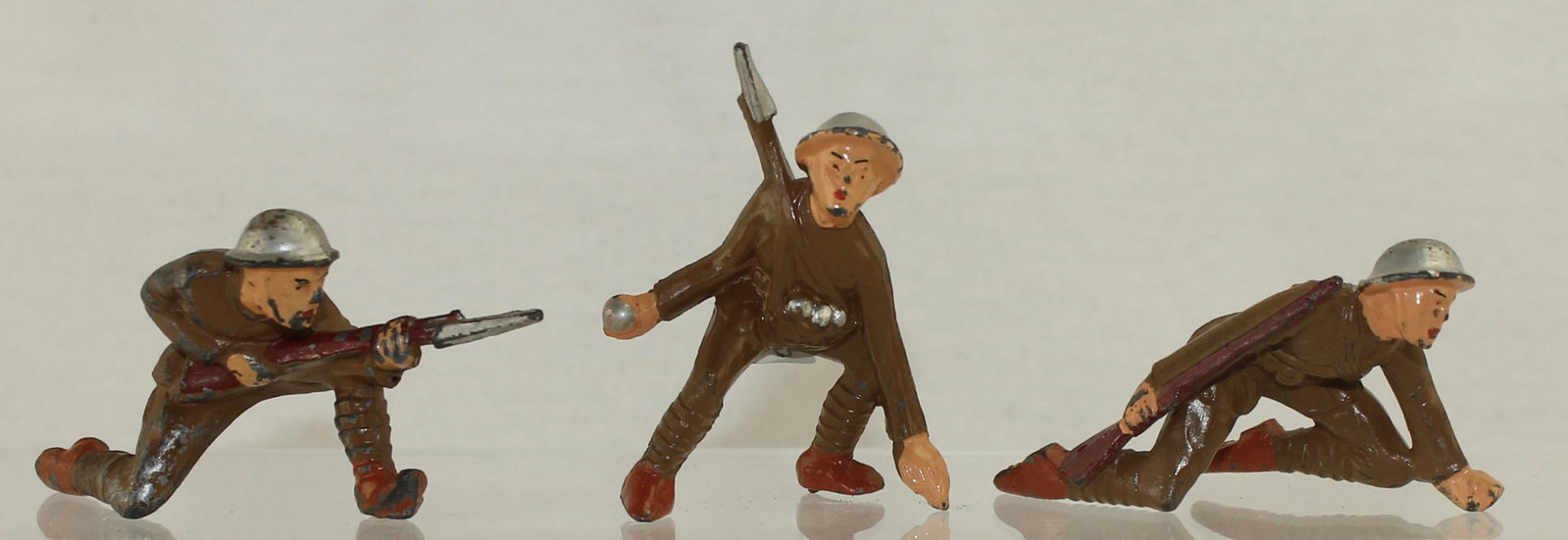 Manoil Lot Combat Troops: Manoil Dimestore. Lot includes M66 Kneeling with Bayonet, M67 Crouching with Grenade and M71 Crawling Scout with Gun. 3 Pieces. Condition Good to Very Good. No Box.