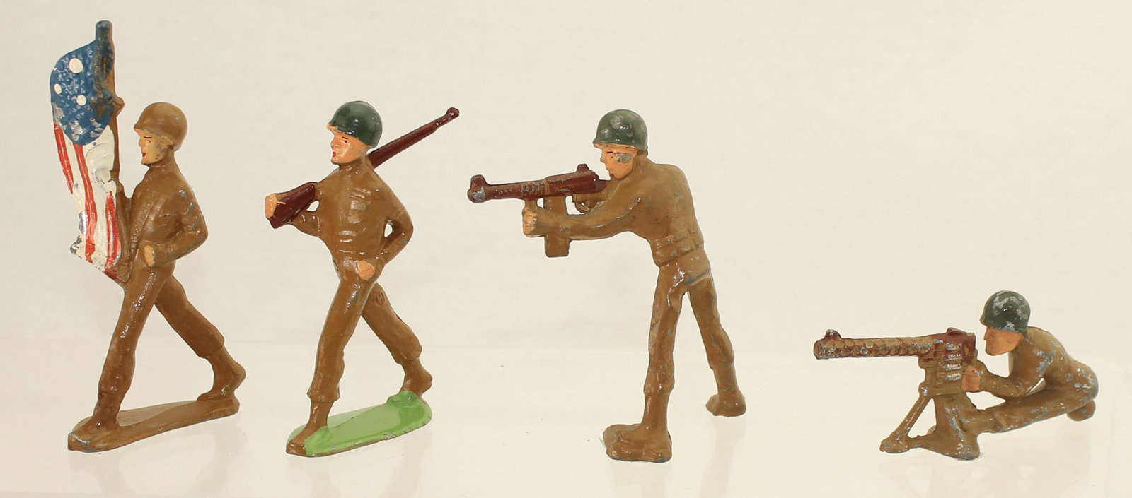 Manoil Lot Skinny Figures: Manoil Dimestore. Late 1945 Production Skinny Series. Lot includes M170 Flag Bearer, M171 Parade Figure, M172 Tommy Gun and M173 Machine Gunner Sitting. 4 Pieces. Condition Very Good to Excellent. Fla