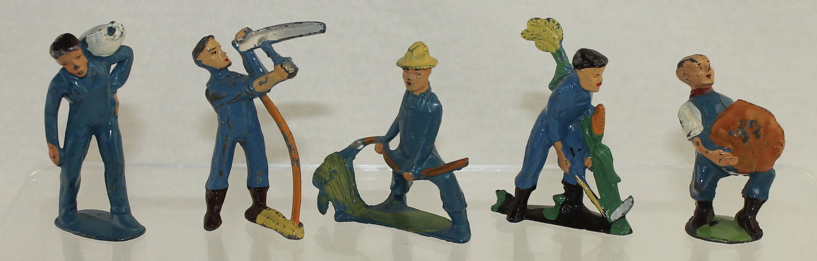 Manoil Lot Farmers: Happy Farm Series. Lot includes M132 Man Carrying Sack, M134 Farmer Sharpening Scythe, M136 Farmer Cutting with Scythe, M137 Farmer Cutting Corn and M141 Farmer Carrying Pumpkin. 5 Pieces. Condition V