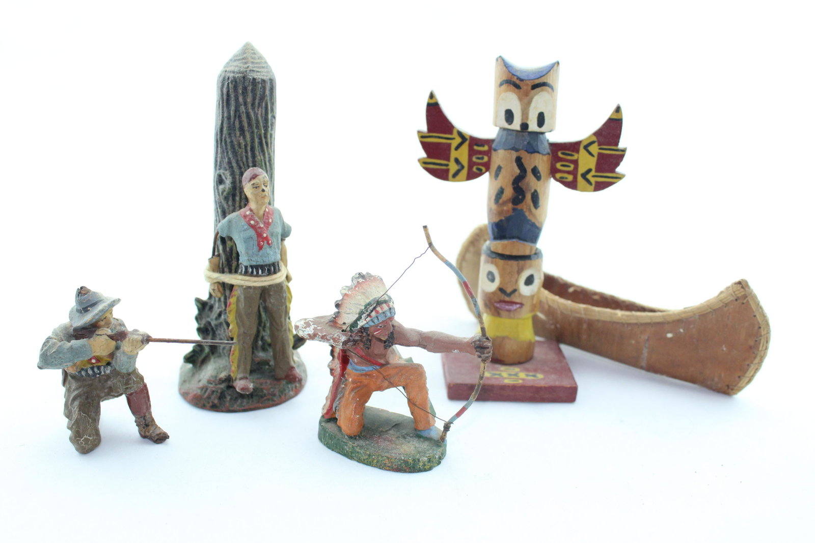 Elastolin Western Group: Five pieces, 1930s-40s, 60 mm Elastolin composition figures, unknown souvenir totem pole and canoe, G/VG, cowboy tied (arms damaged), cowboy firing rifle and Native American firing bow, VG.