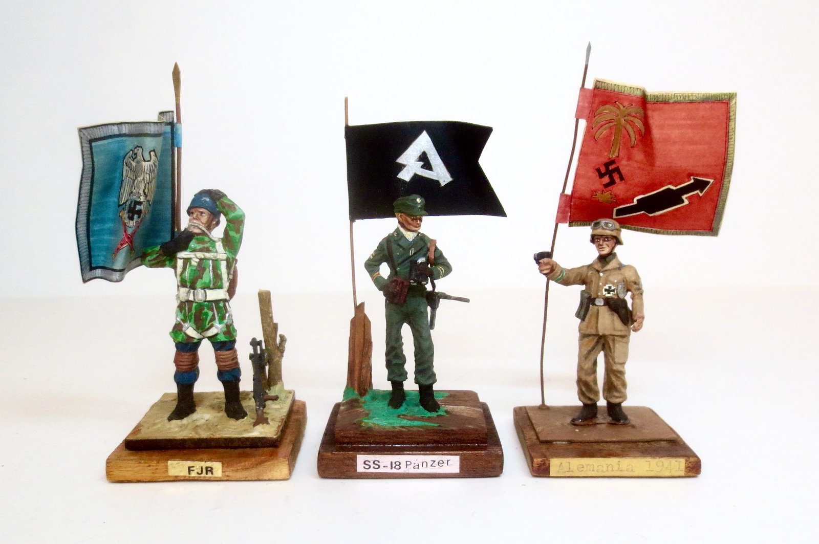 Military Models WWII Germans: Fallschrimjager with Flag, SS-18 Panzer with Flag, and Alemania 1941. 3 pieces. Near mint to very good condition (pistol tip broken). Unboxed.