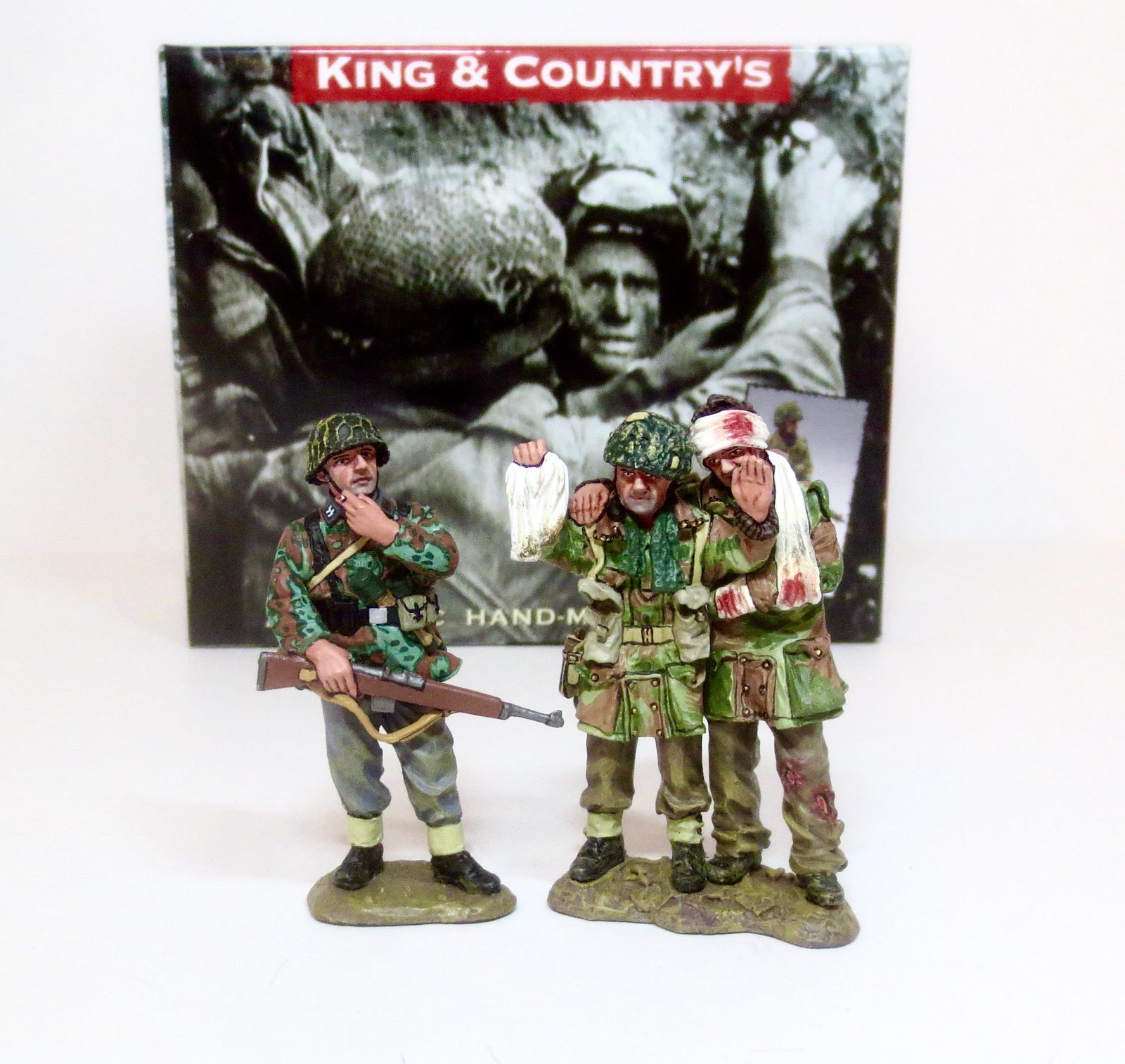 King & Country #MG032 "Captured": Sadly, all too many of the British 1st Airborne Division at Arnhem ended up killed, wounded or captured. Here, a casually smoking SS Panzer Grenadier guards two Paras… one seriously wounded. A poign