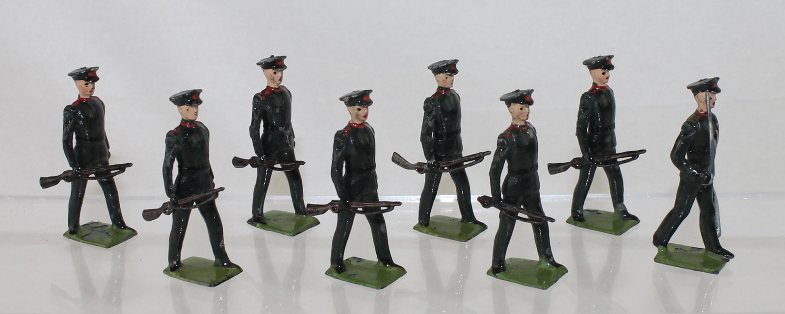 Britains Set 2091 Rifle Brigade Number 1 Dress: At The Trail. Circa 1954-1959. 8 Pieces. Condition Very Good. Embellishments to Red Cap Badges, Collars and Epaulettes. One Rifle Butt Missing. One Small Dent in Groin. No Box.
