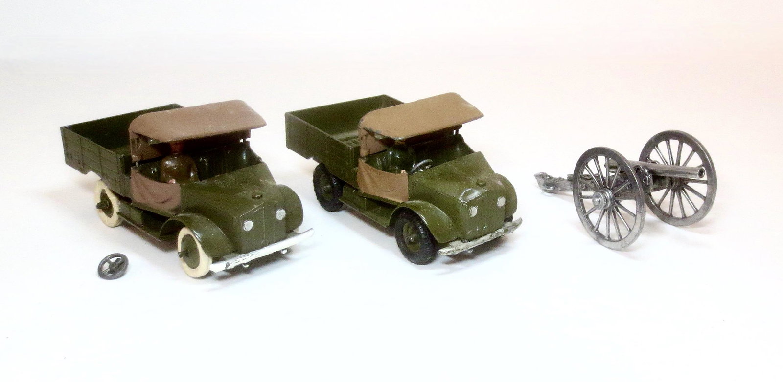 Britains #1877 Two Beetle Lorrys: In excellent to good condition (one loose steering wheel, and one flat tire). Plus Pewter Ordinance Gun in excellent condition. 3 pieces. Unboxed.