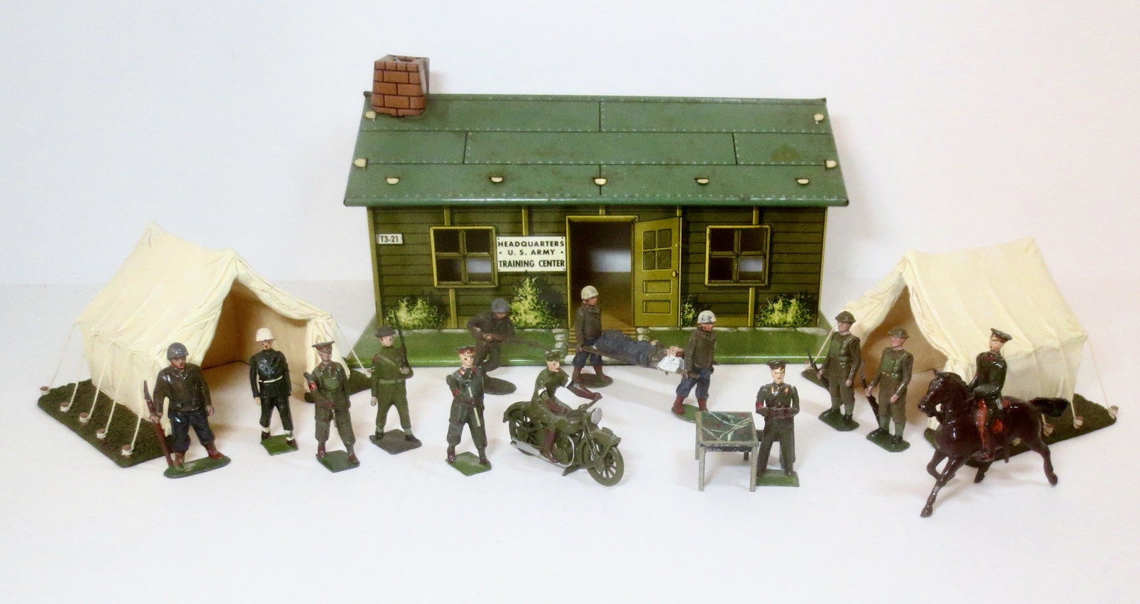 Marx Tin U.S. Army Training Center: With Britains Tents, and an assortment of U.S. Soldiers. Timpo plastic stretcher bearers & Infantry man running with rifle. Plus an assortment of Britains lead Khaki soldiers & Timpo guard. 18 pieces.