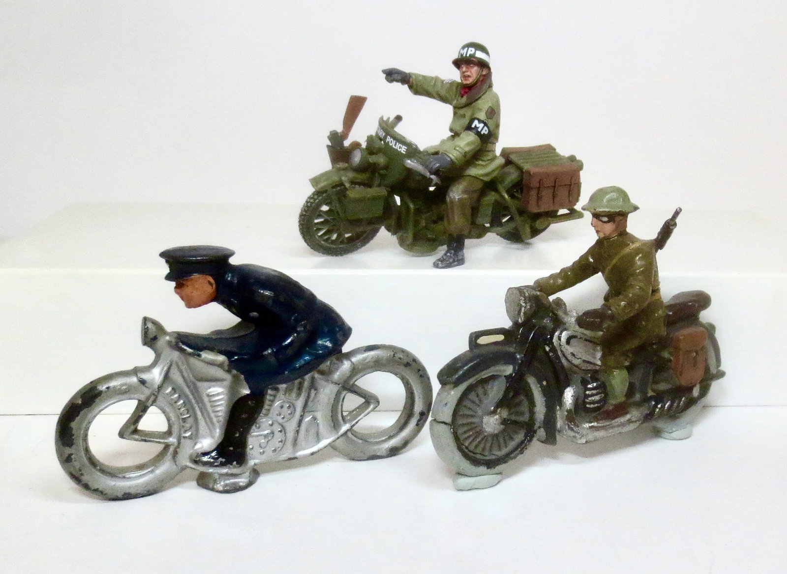 Assorted Military & Police Motorcycles: Barclay Police Motorcycle, King & Country Military Police Motorcycle, and Composition. Military Motorcycle. Near mint to very good condition (composition motorcycle missing kickstand). 3 pieces.