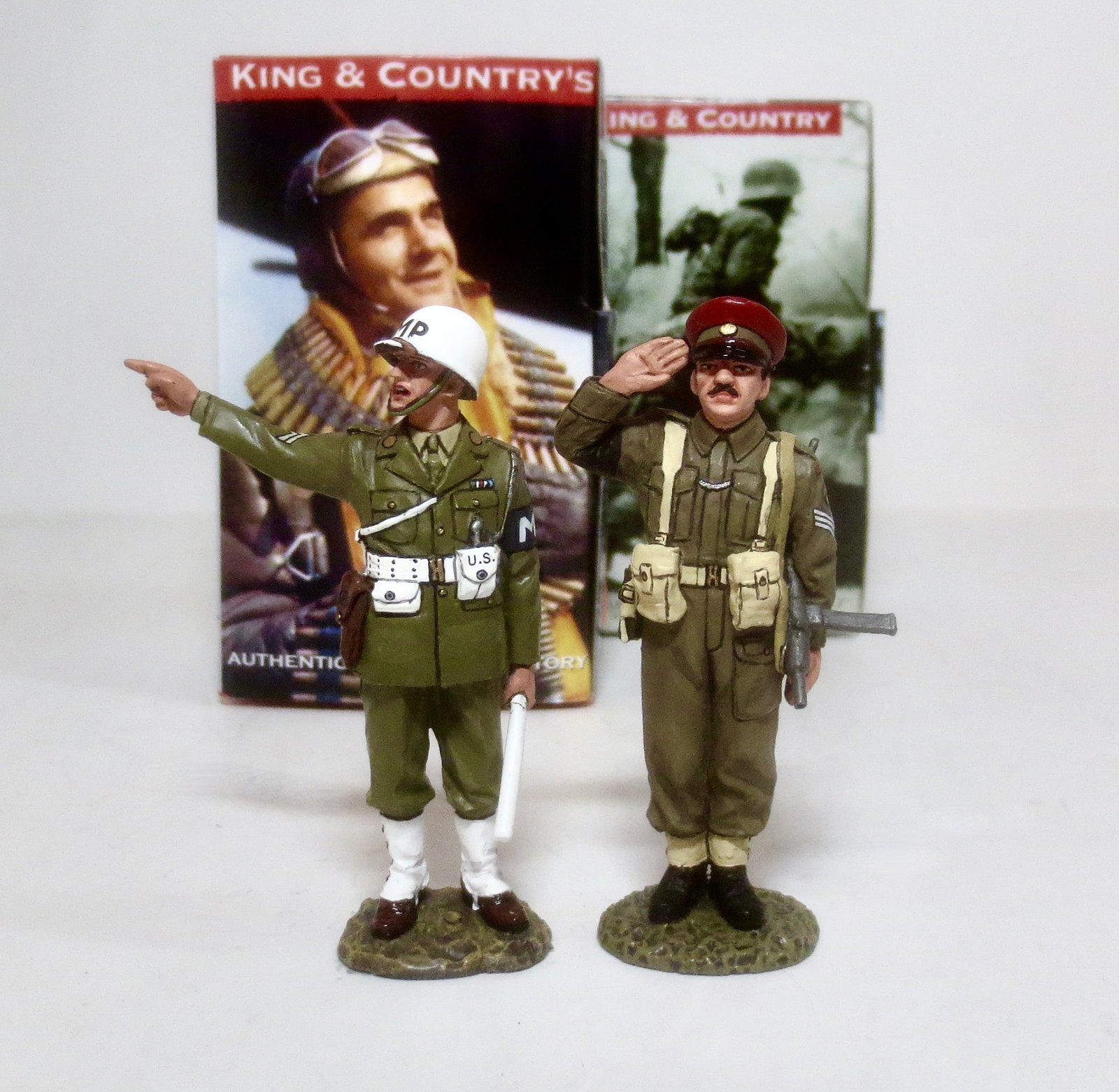 King & Country WWII Military Policemen: #DD155 Saluting British Redcap Military Policeman, and #AF010 Pointing Military Policeman. 2 pieces. Both retired. Mint condition. Boxes excellent.