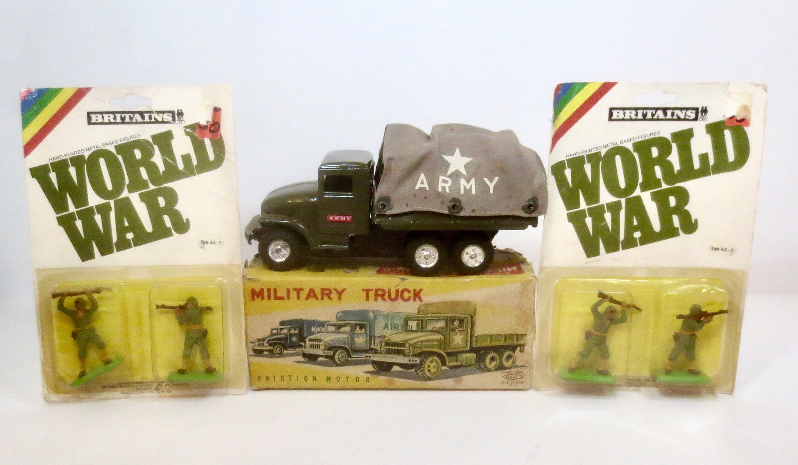 Haji Friction Motor 8" Long Military Truck: With Britains World War #AS2 Soldier Packs. Small dent on truck side bed, otherwise in pristine condition with a very good original box. Britains figures mint in packs.