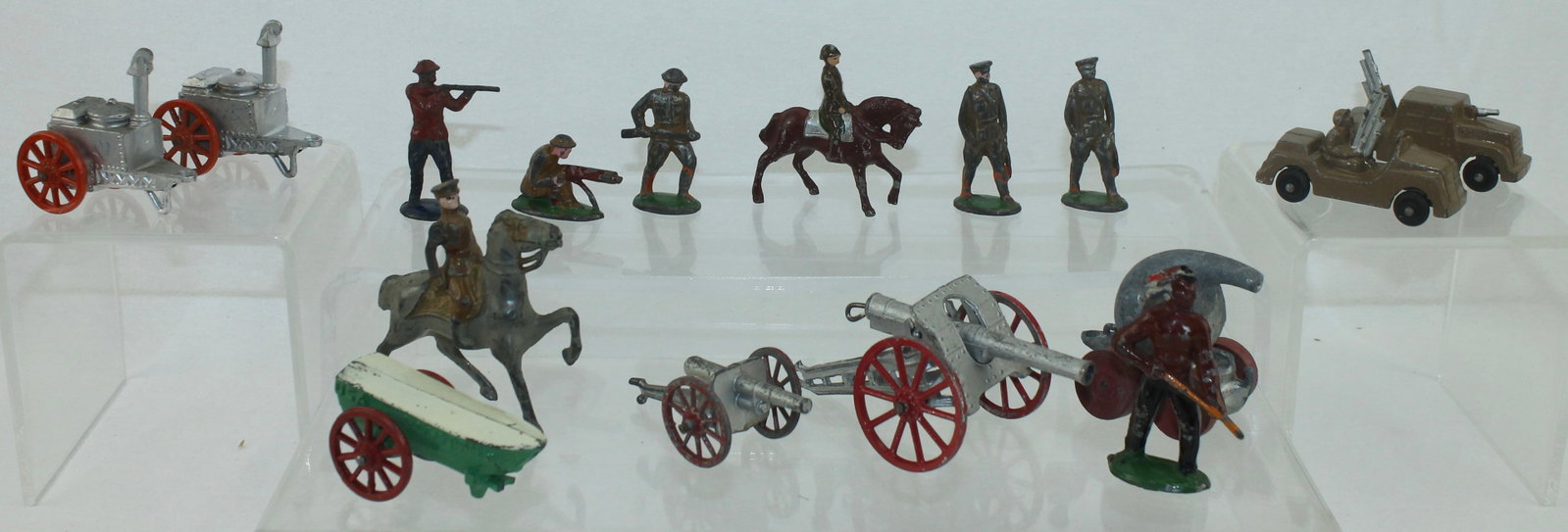 Lot of Early Barclay Figures and Vehicles: Lot includes 2 Cannons, 2 Field Kitchen Trailers, Gas Trailer, Boat, Mounted Officer and 8 Troops Advancing Firing. 16 Pieces. Condition Good. Officer Sword Broken. One Advancing Rifle Barrel Broken. 