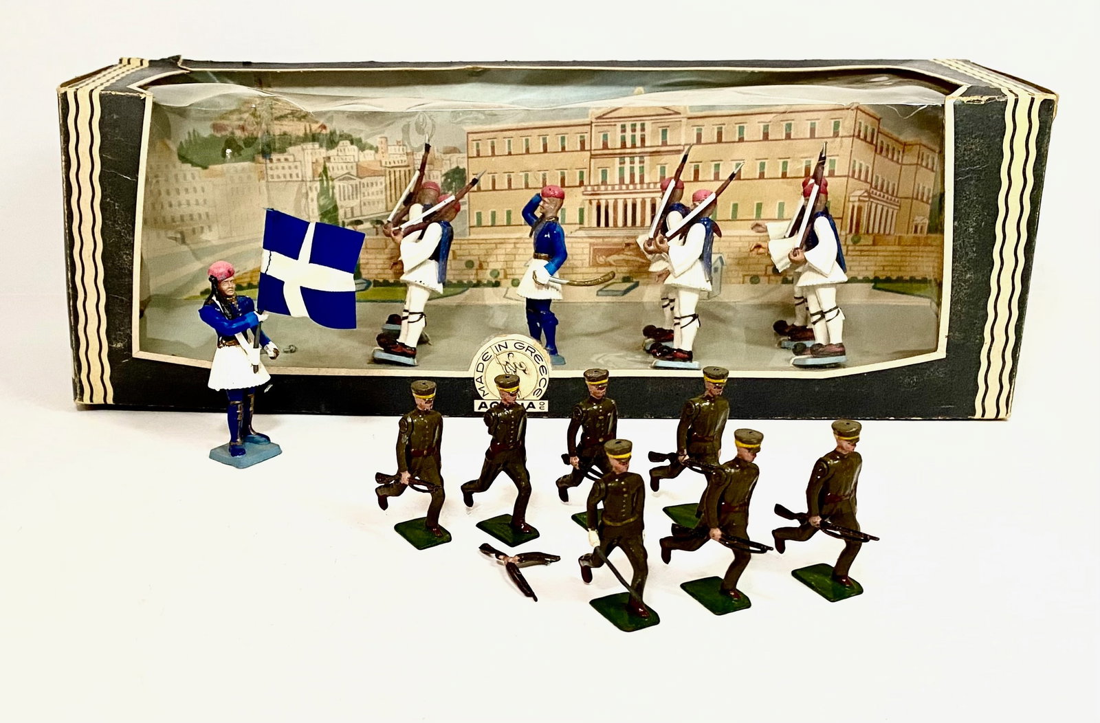 Aohna & Britains Greek Soldiers Sets: 15 pieces. Aohna plastic figures in original window display box (one loose figure), excellent condition, box fair (cellophane damage). And, Britains from set #171 (one broken arm, one broken rifle), t