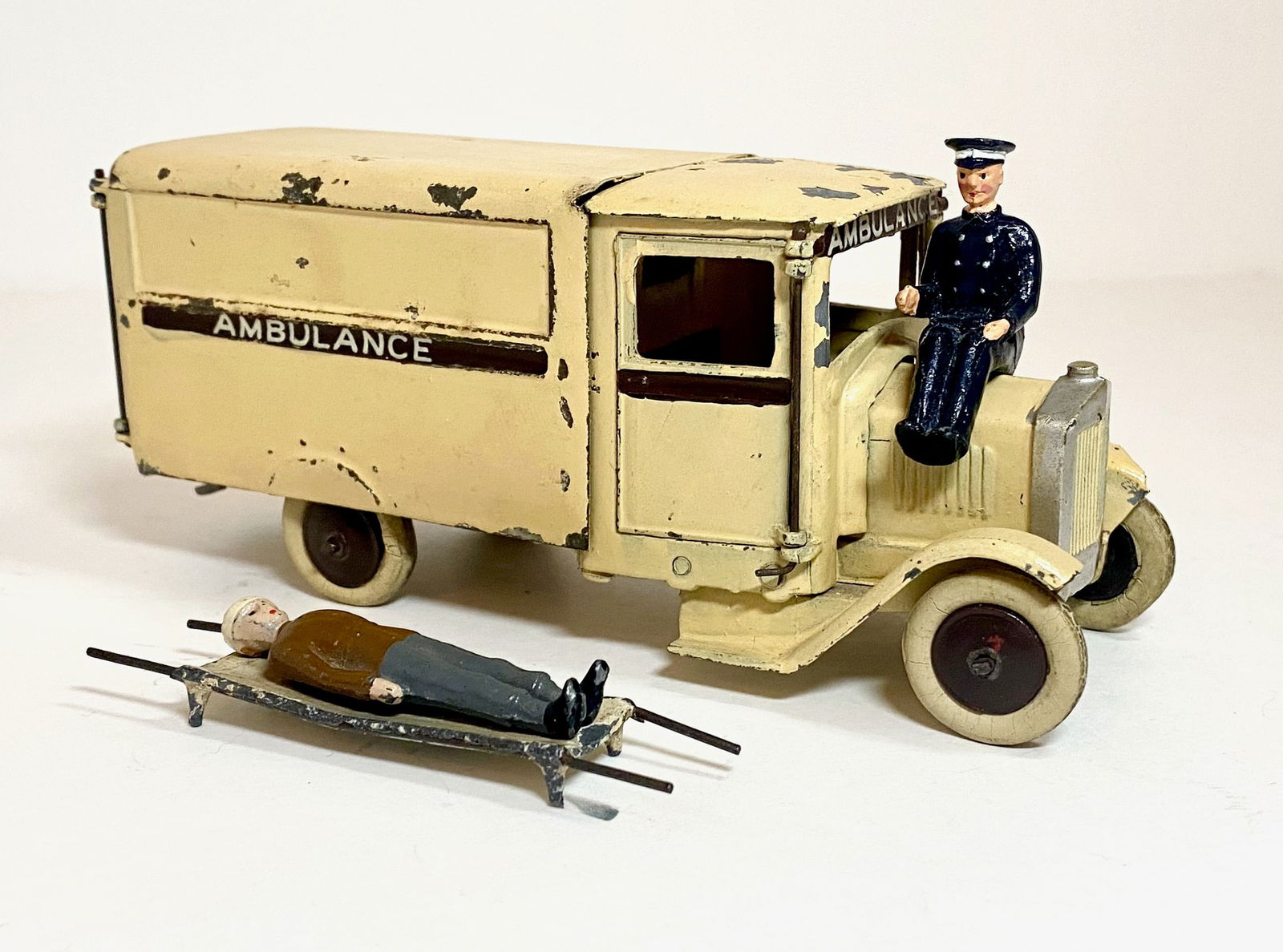 Britains #1514 RARE Corporation Ambulance: Circa 1937-1941. Corporation Motor Ambulance, 1st version square nose, cream with brown midbody stripe & wheels, with driver, stretcher & wounded. 4 pieces. Condition good, paint chips in areas, drive