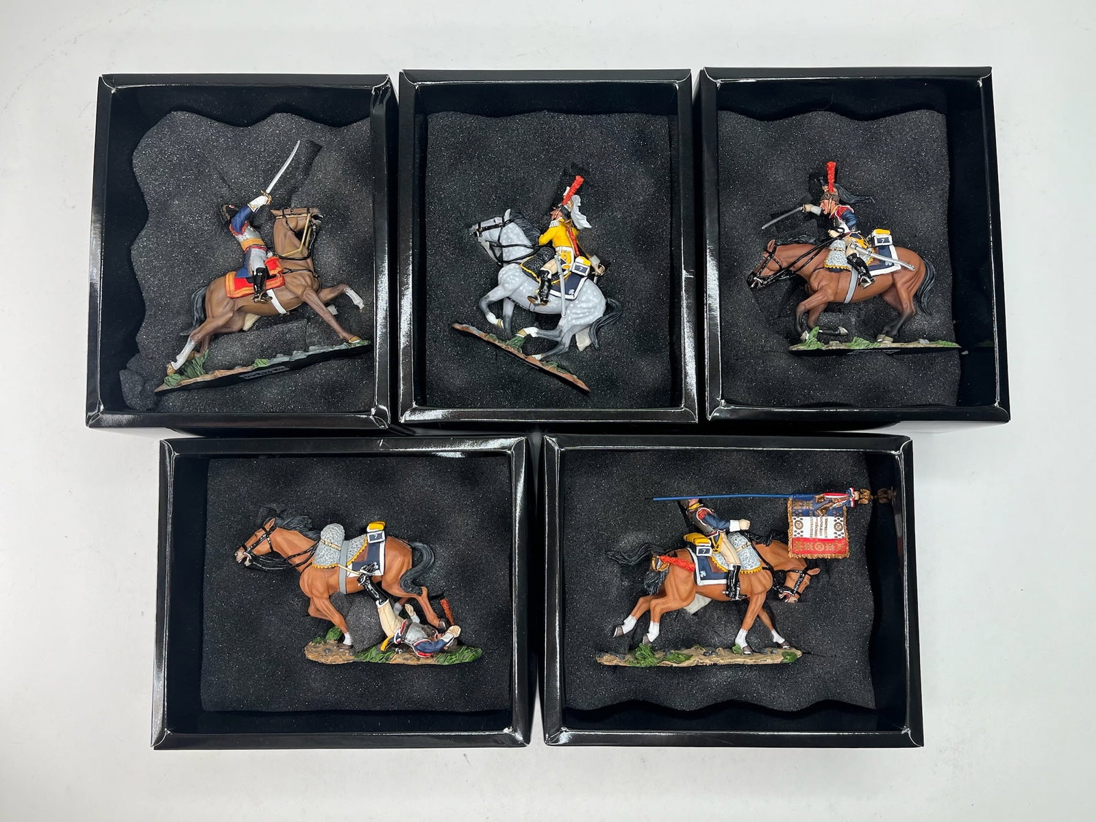 King & Country Napoleon Horseback Assortment: NA111 Cuirassier General, NA112 Wounded Flagbearer, NA113 Charging Trumpeter, NA114 Charging Sword Forward, and NA115 Falling Off Horse. 5 Pieces. Condition Excellent. Boxes Very Good.