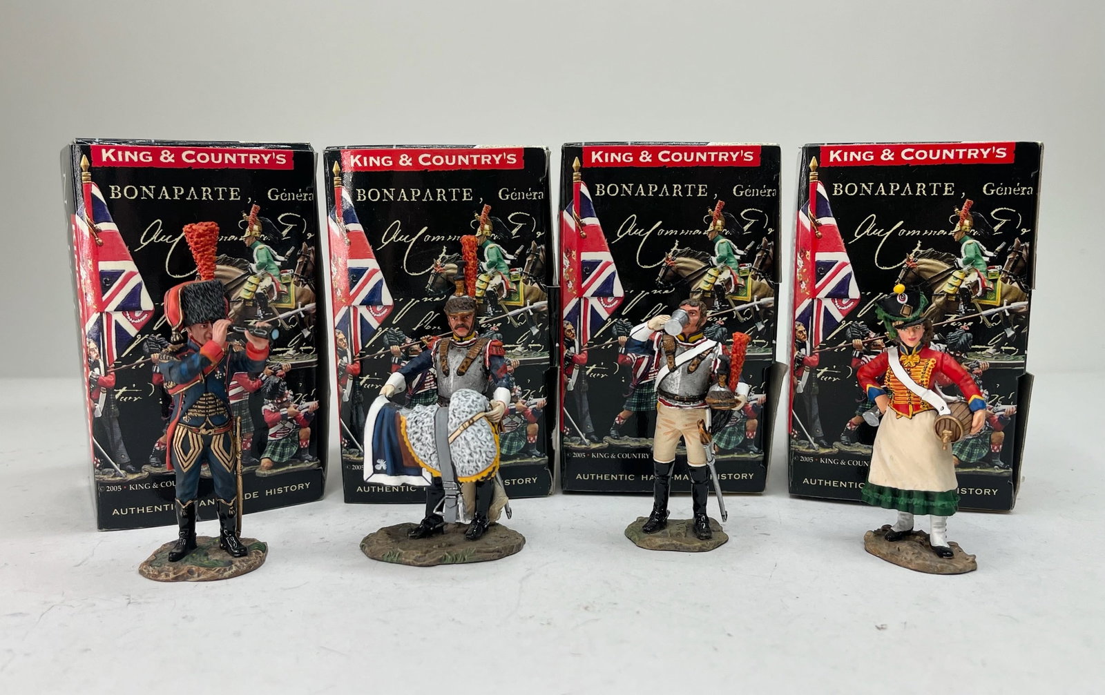 King & Country Age of Napoleon Figure Assortment: NA065 Artillery Officer with Sword, NA122 Standing Cuirassier with Saddle, NA123 Cuirassier Drinking, and NA124 Cantiniere. 4 Pieces. Condition Excellent. Boxes Good.
