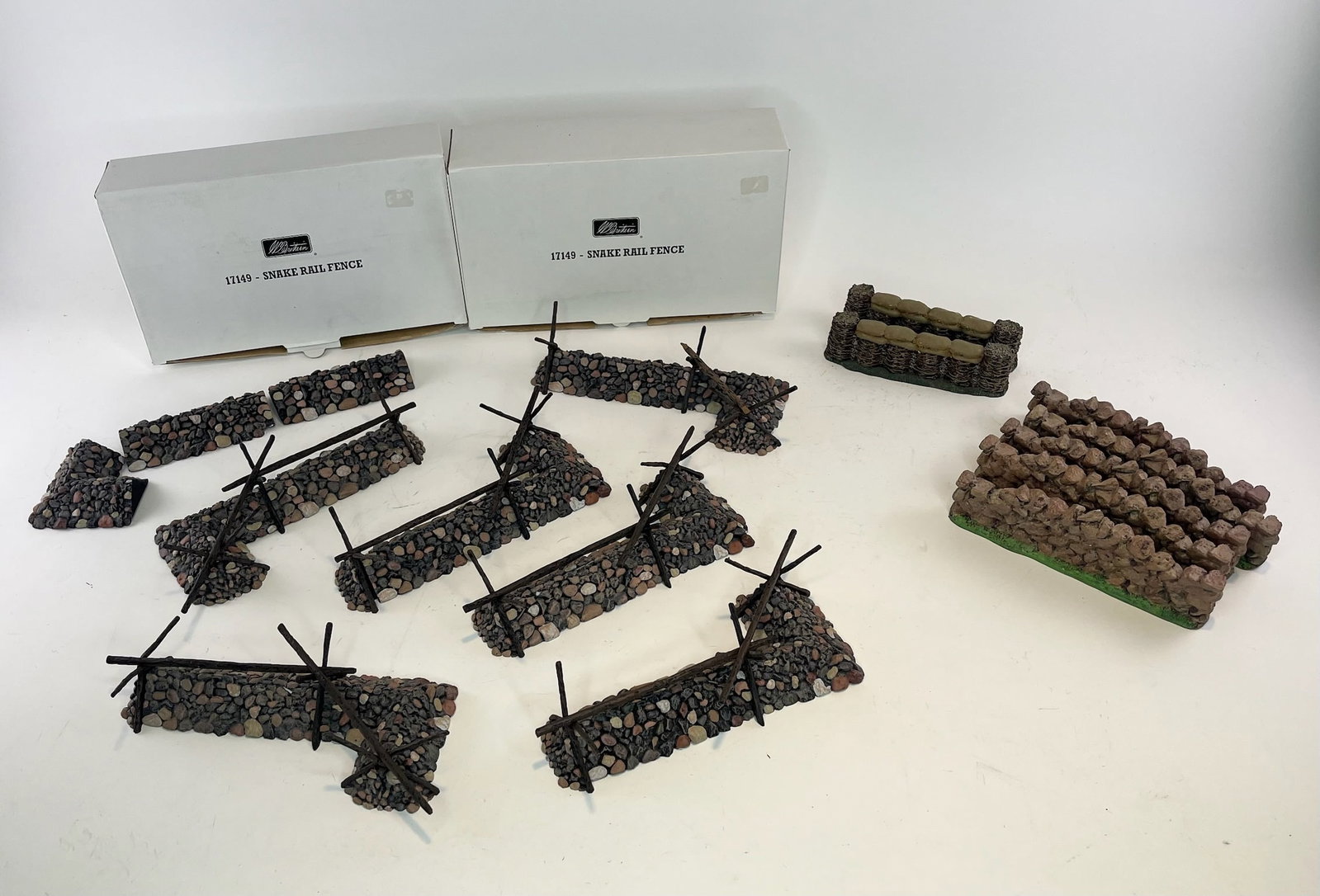Britains Snake Rail Fence and Wall Assortment: 5 Complete 17149 Sets, 2 with boxes. Boxes Very Good. Each set contains 7 pieces. 10 Miscellaneous Snake Rail Fence Pieces. 5 Stone Walls and 2 Straw Barricades. 52 Pieces Total. Condition Excellent. 