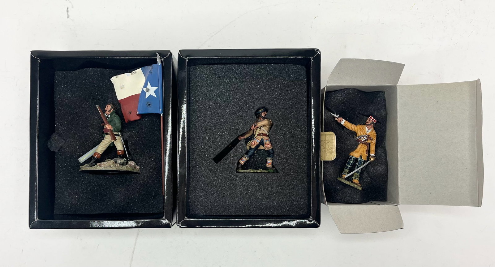 King & Country Remember The Alamo Assortment: Includes RTA022 John McGregor of Scotland, RTA033B Texas State Flag, and RTA040 Swinging Rifle. 3 Pieces. Condition Excellent. Boxes Excellent.