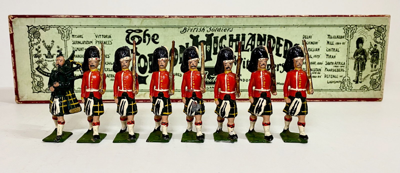 Britains #77 Gordon Highlanders: Pre war issue. Marching at the slope with piper. 8 pieces. Excellent condition, in Whisstock illustrated label box. Box very good.